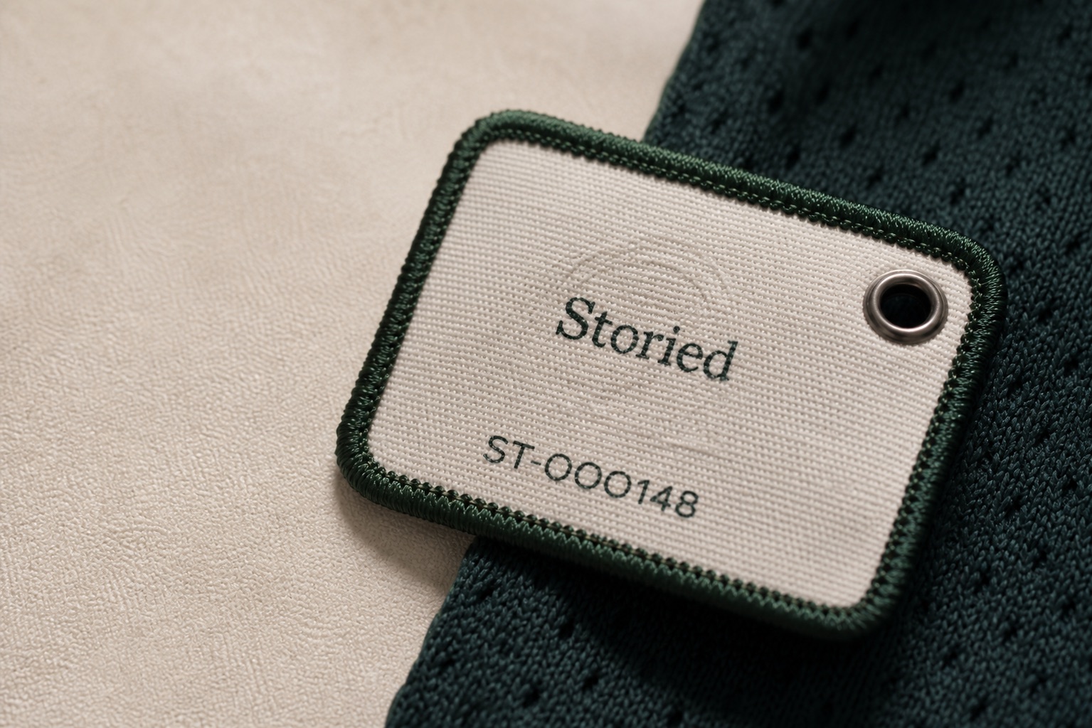 Macro concept photograph of a cream woven Storied NFC tag on dark green jersey fabric